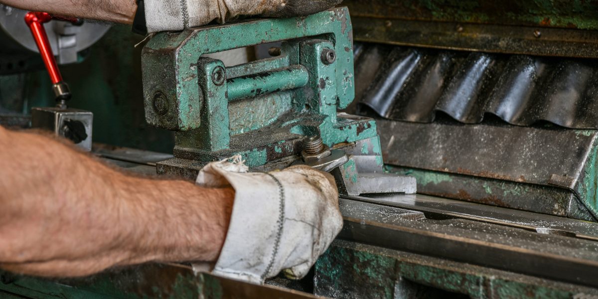 The worker installs the fixture on the machine bed by tightening the nuts with a wrench.
